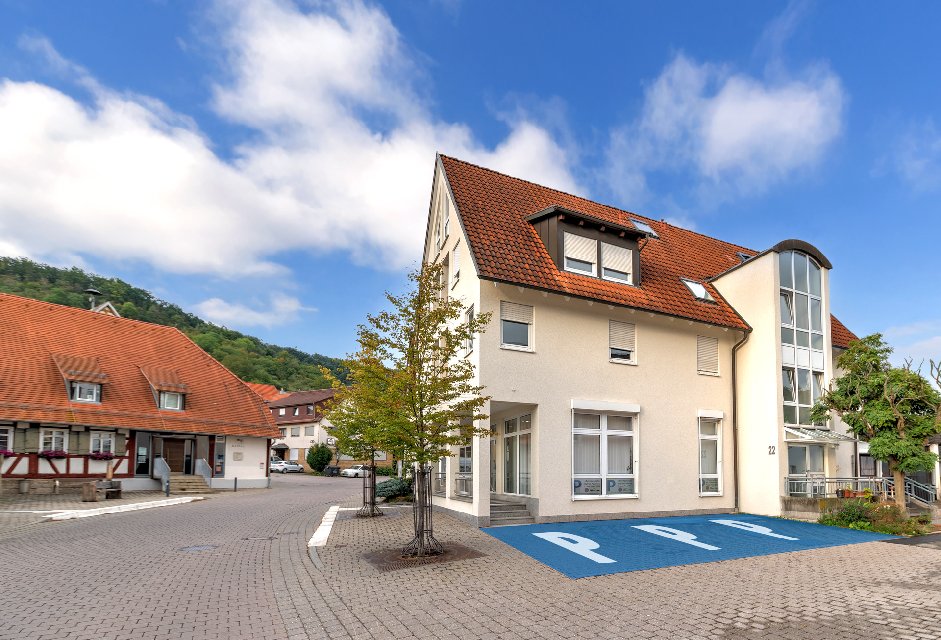 Ansicht des Praxisgebäude von außen und eingezeichneten Parkplätzen davor